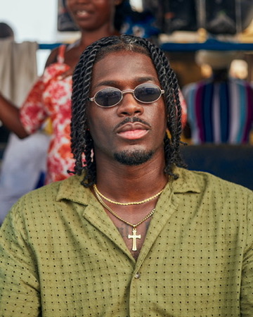 Portrait of Elikem in green with oval sunglasses